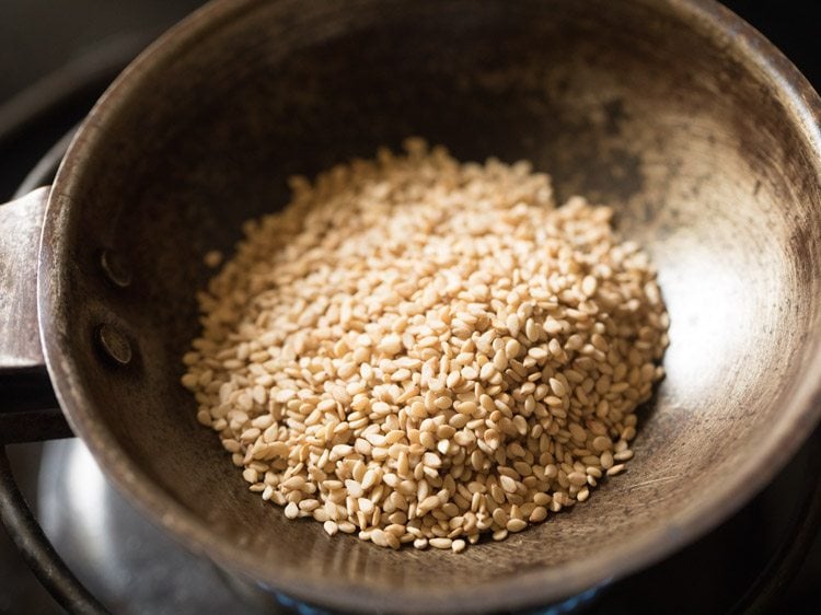 white sesame seeds added to a pan on heat.