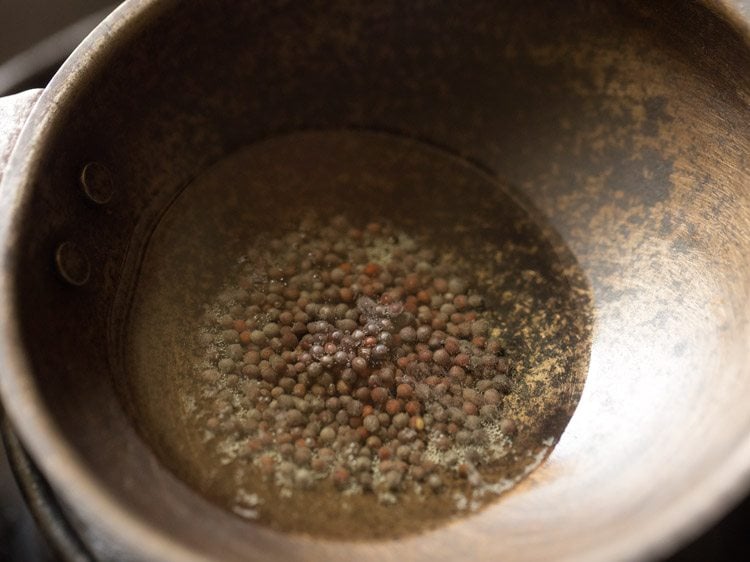 mustard seeds added to hot sesame oil in a small pan. 