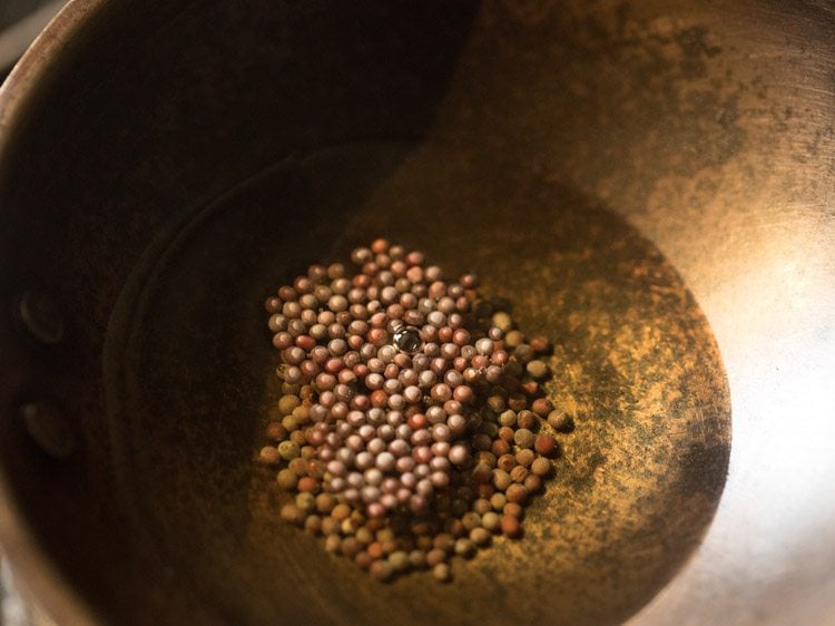 mustard seeds added to hot sesame oil in a pan. 