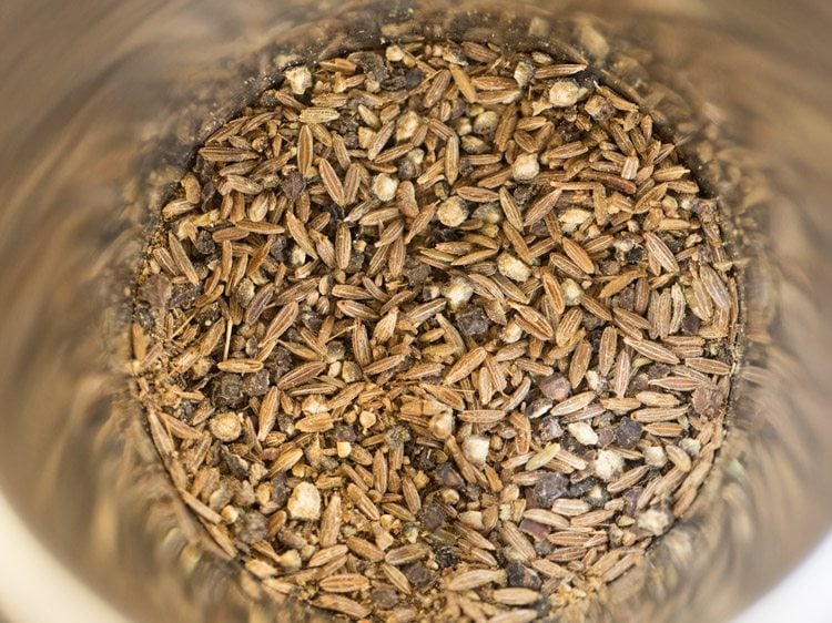 cumin seeds and black pepper added  in a mortar for making vazhakkai fry. 