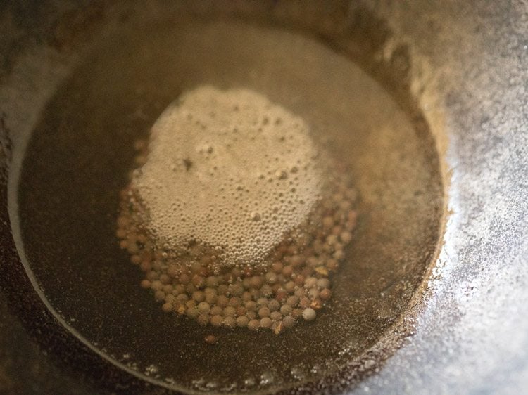 mustard seeds added to hot coconut oil for making vazhakkai fry. 