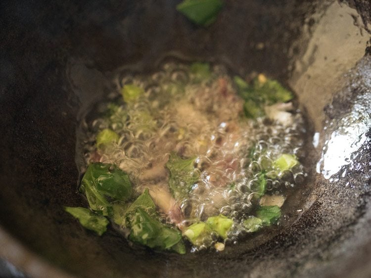 thickly sliced pearl onions, chopped or slit green chili and curry leaves added to pan. 