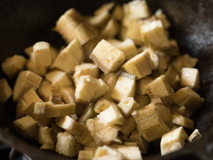 chopped raw banana added to pan for making vazhakkai fry. 