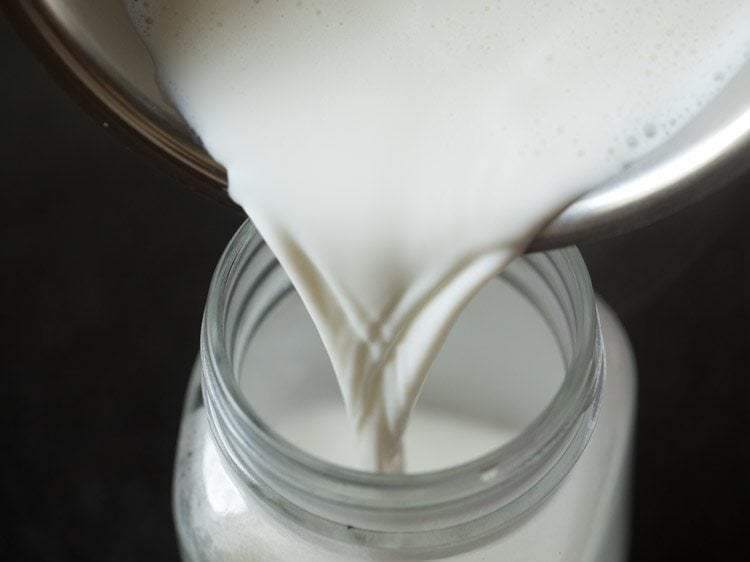 pouring the hot milk into a mason jar to shake into cappuccino foam.