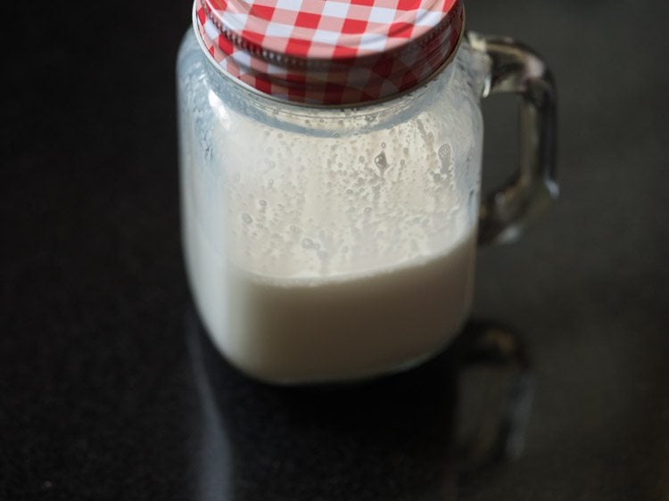 milk in a glass jar with a handle and a red and white gingham lid.