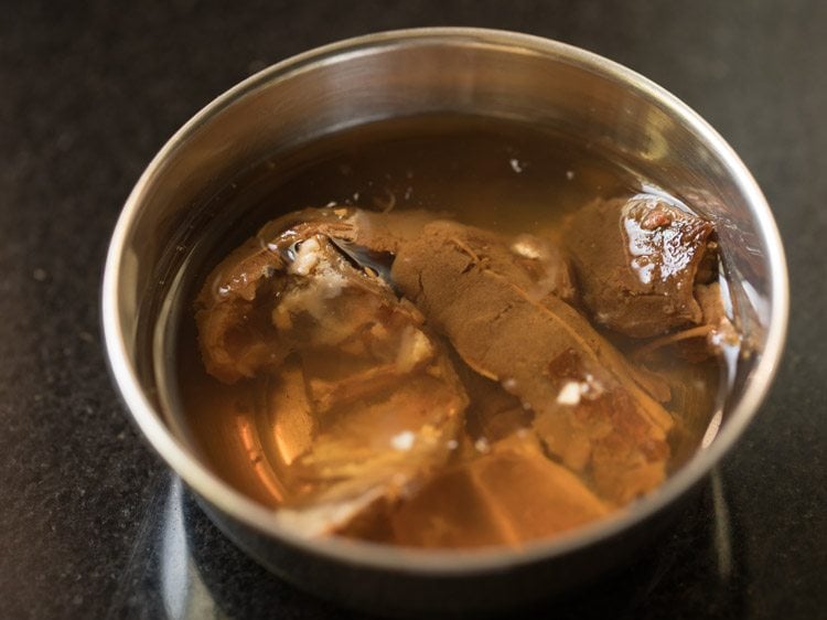 soaking tamarind in hot water for making tamarind pulp for coconut milk rasam. 