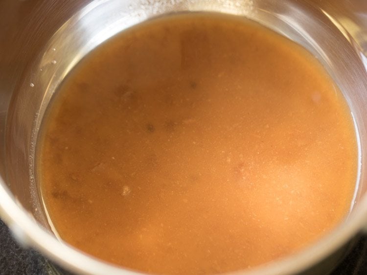 tamarind pulp poured in a pan for coconut milk rasam. 