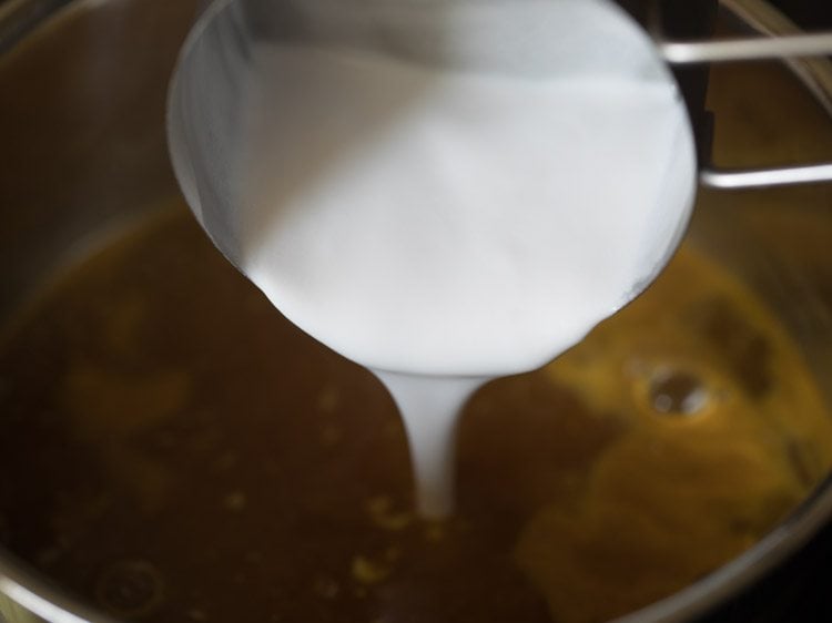 adding thick coconut milk to tamarind mixture for coconut milk rasam. 