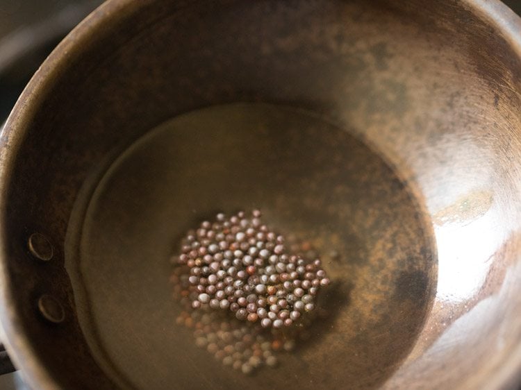 mustard seeds added to hot coconut oil for thengai paal rasam.