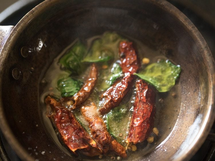 dried red chilies, asafoetida and curry leaves added to hot oil for thengai paal rasam.