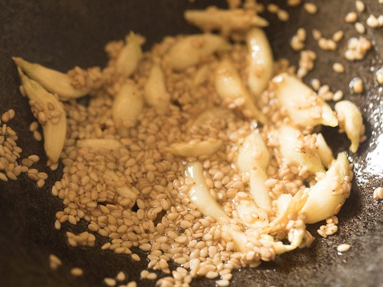 stirring the sesame seeds and garlic together for making dry garlic chutney recipe.