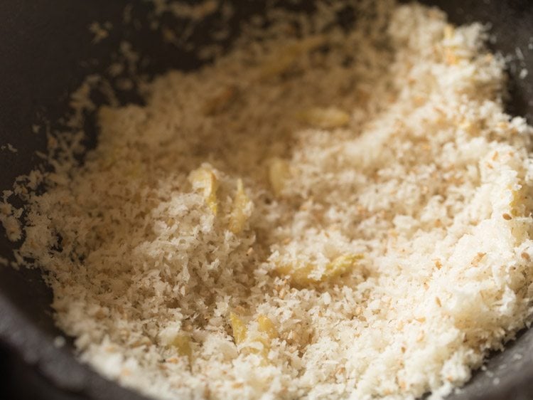 mixing the coconut with the sesame seeds and garlic.