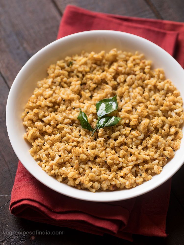 peanut rice garnished with a fried curry leaf sprig and served in a white bowl. 