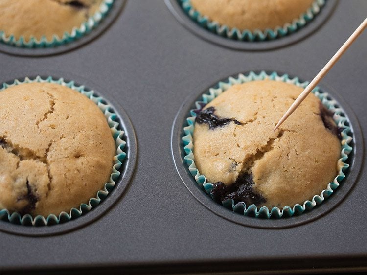 checking the doneness of blueberry muffins with a toothpick