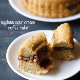 hero shot of two slices of streusel sour cream coffee cake on a white plate with the rest of the cake in the background.