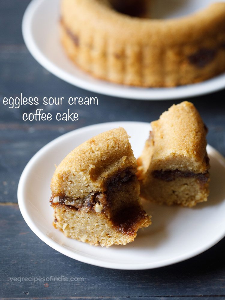 hero shot of two slices of streusel sour cream coffee cake on a white plate with the rest of the cake in the background.