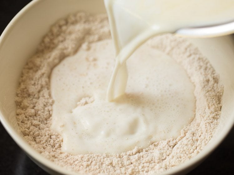 Milk mixture being poured into flour mixture in mixing bowl.