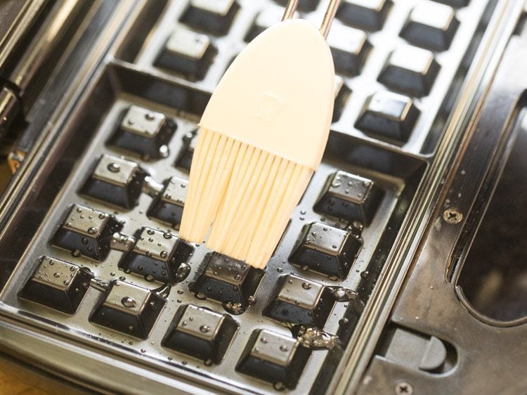 Spreading melted butter on waffle iron.