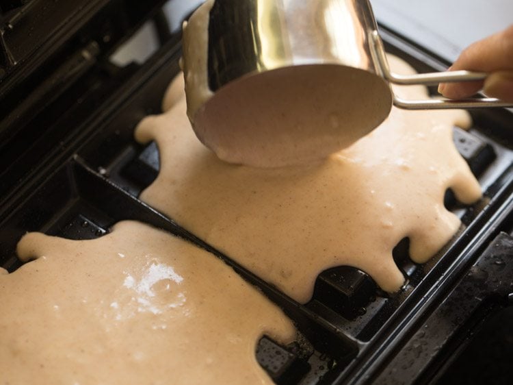 Pouring eggless waffle batter onto waffle iron.