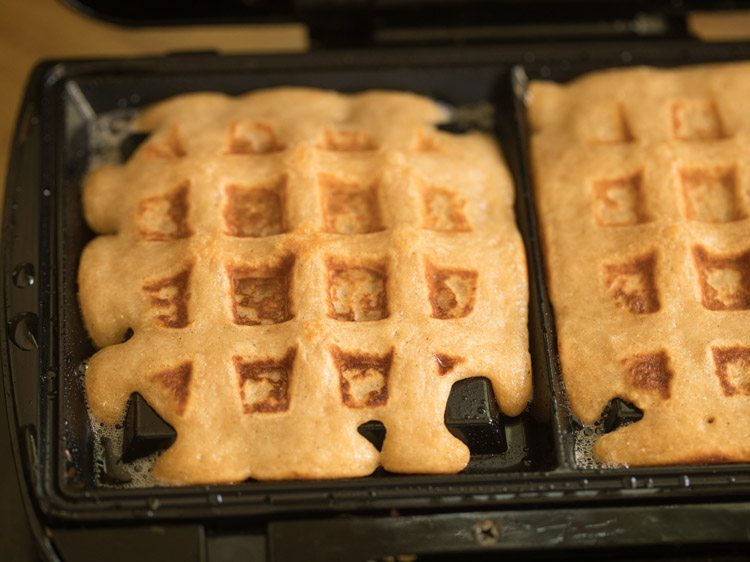 Two eggless waffles cooked in waffle iron.
