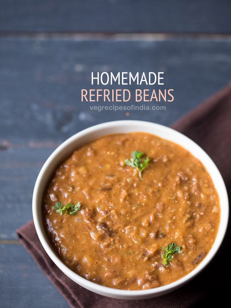 refried beans garnished with coriander leaves and served in a white bowl with text layovers.