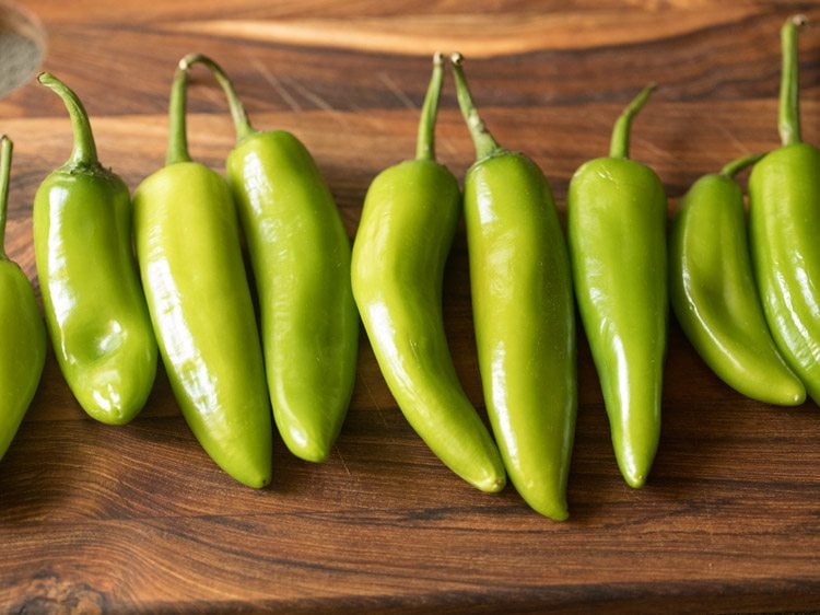 rinsed and wiped large green chilies on a wooden chopping board to make chilli bajji.