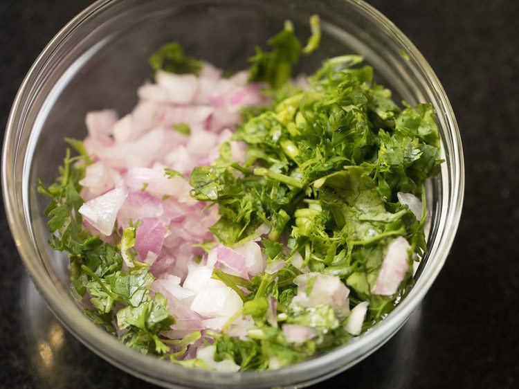 chopped onions and chopped coriander leaves added to a glass bowl. 