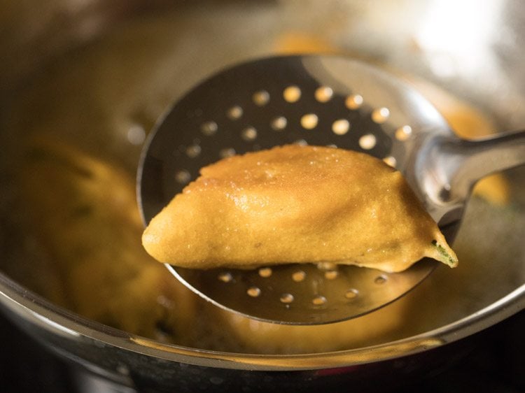 removing fried mirchi bajji with a slotted spoon. 