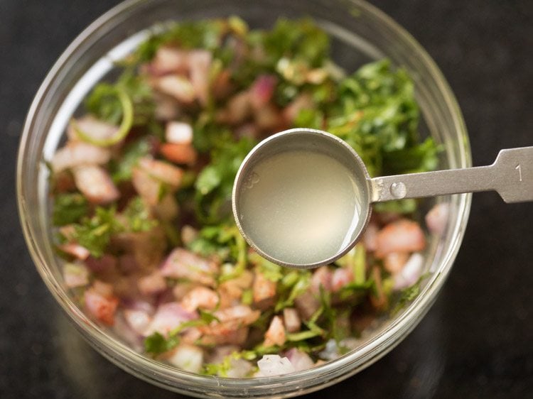 adding lemon juice to the spiced onion-coriander leaves mixture. 