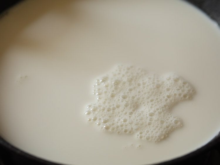 heating milk in a heavy pan for mishti doi recipe. 