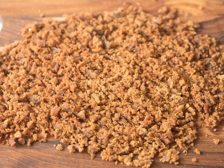 chopped palm jaggery on a wooden chopping board for mishti doi recipe. 