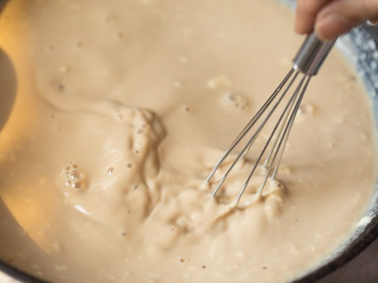 mixing the curd in the milk-jaggery mixture with a whisk. 