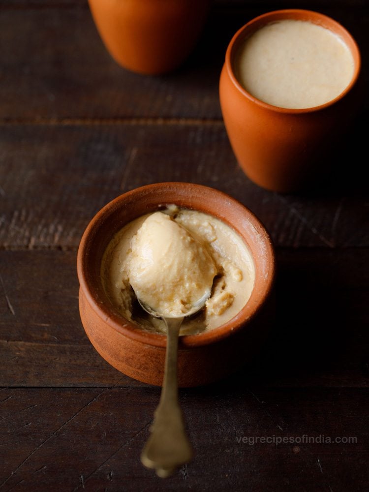 mishti doi served in an earthen bowl with some scooped in a spoon and text layover. 