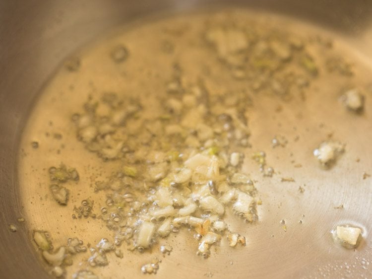 frying garlic in hot olive oil in pan for refried beans recipe. 