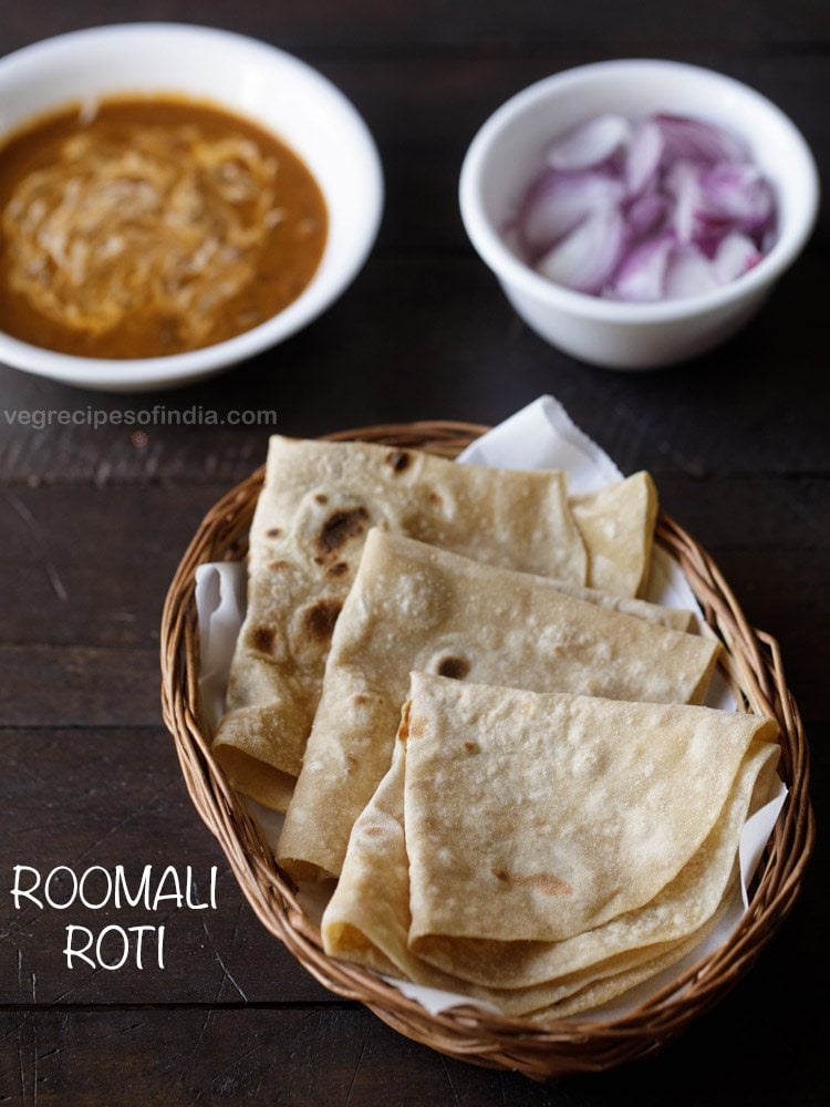 rumali roti folded and served in a basket with a bowl of curry and a bowl of onions kept in the background and text layover.