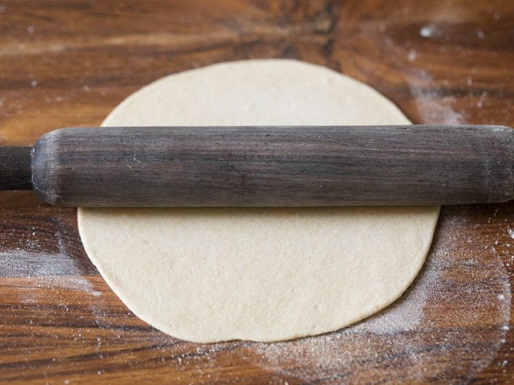 rolling the dough ball with a rolling pin. 
