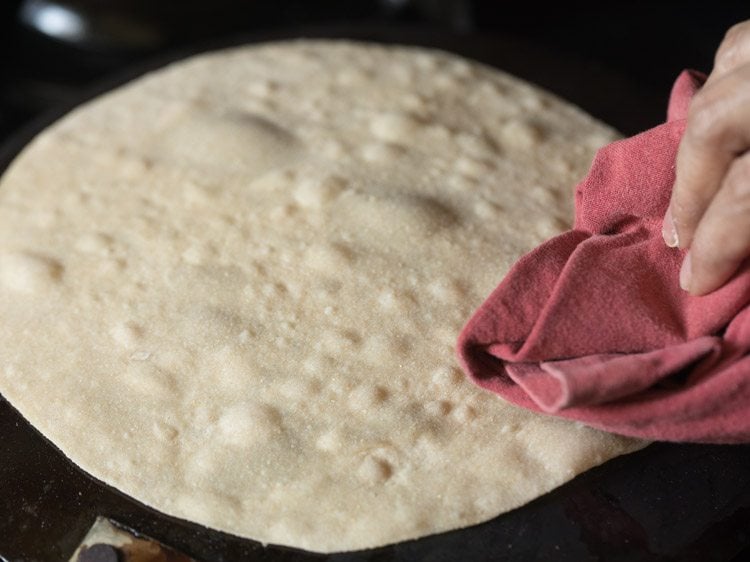 roasting rumali roti by pressing with a folded cotton napkin. 