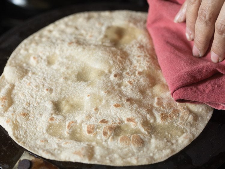 roasting other side of rumali roti by pressing with a folded cotton napkin. 