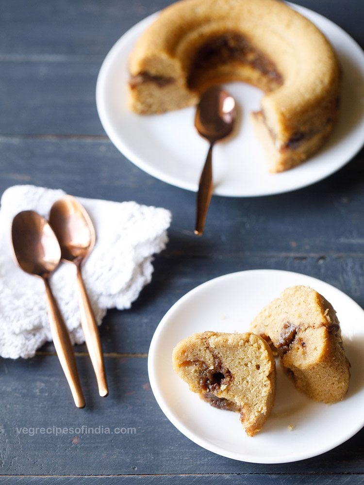 hero shot of two slices of streusel sour cream coffee cake on a white plate with the rest of the cake in the background.