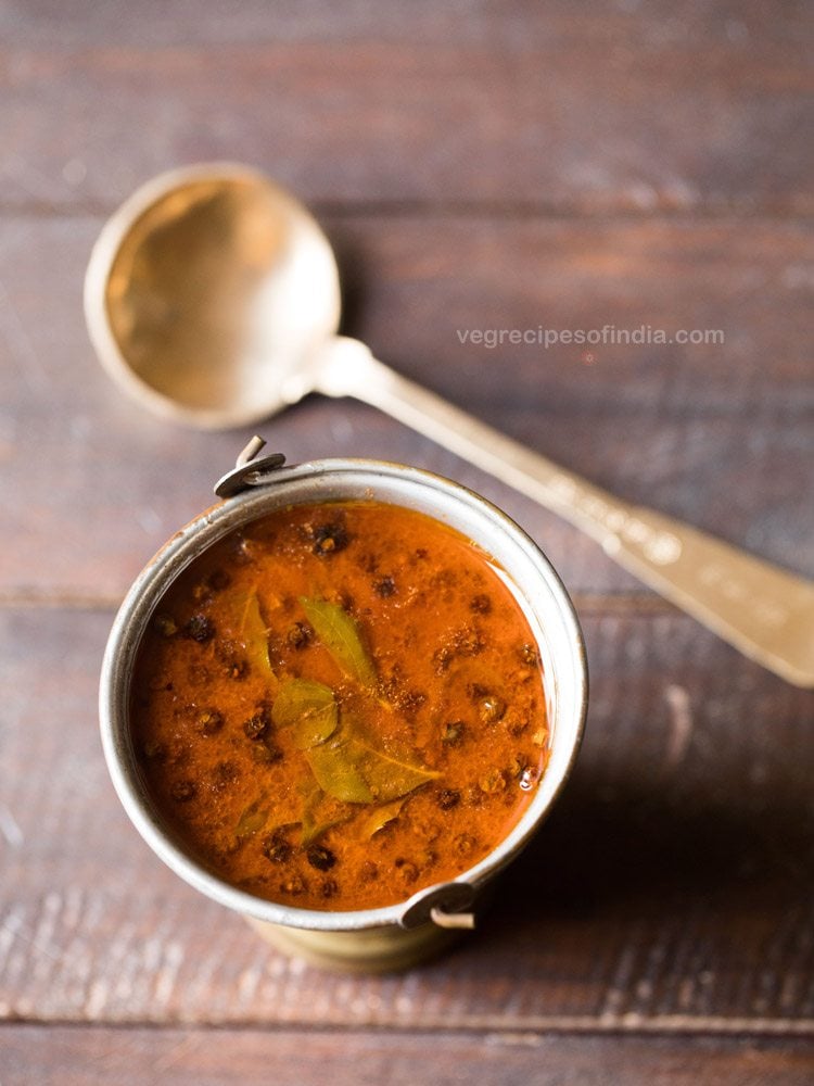 vatha kulambu served in a fancy brassware with a spoon kept in the background. 