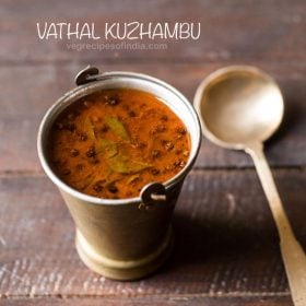 vatha kulambu served in a fancy brassware with a spoon kept on the right side and text layover.