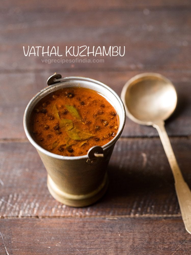 vatha kulambu served in a fancy brassware with a spoon kept on the right side and text layover.