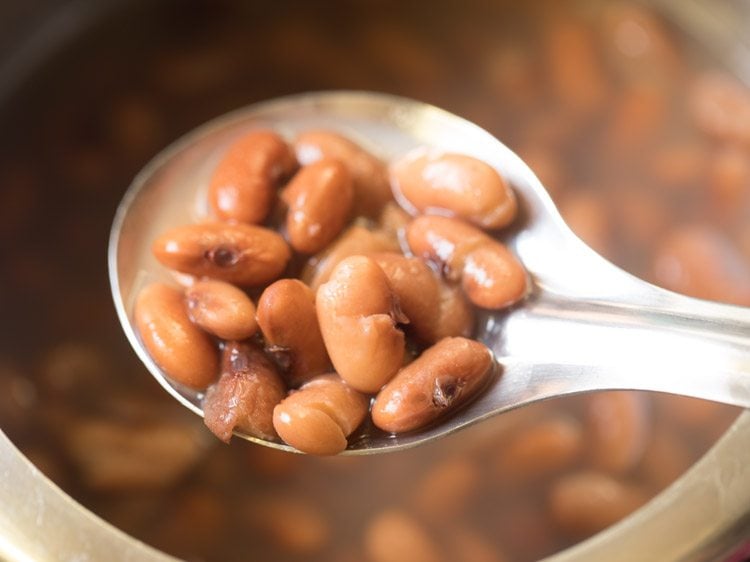 spoonful of cooked rajma showing that they are soft enough that some are breaking open. 