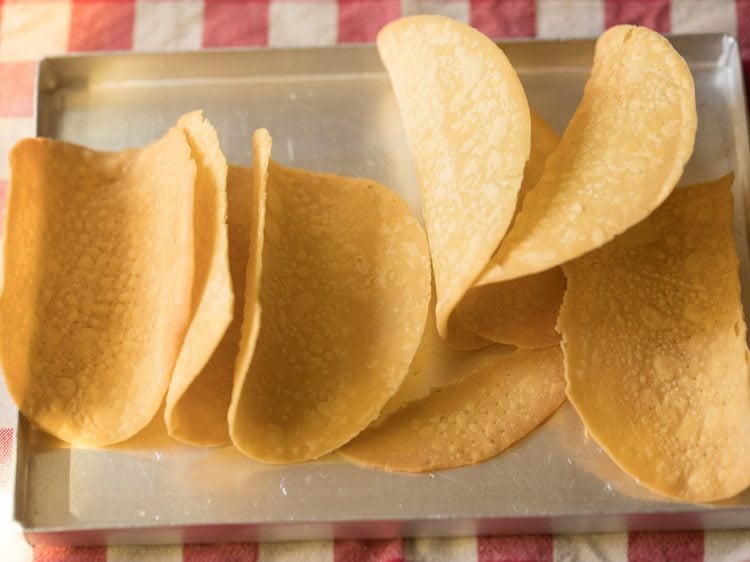 hard corn tortilla shells on a baking tray. 