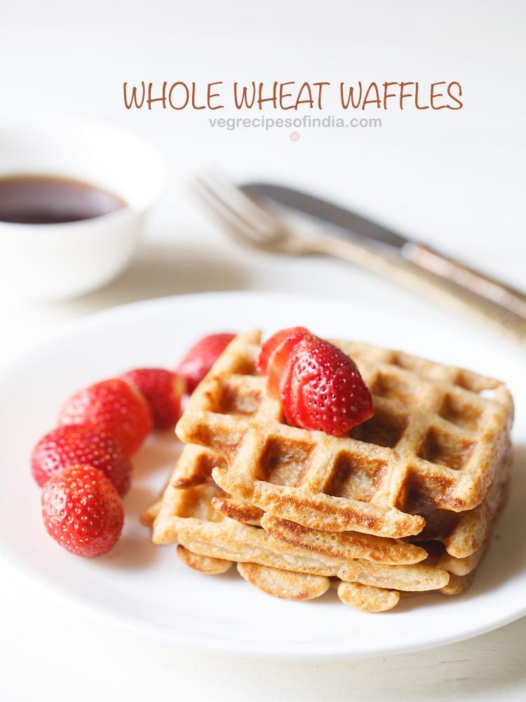 Whole wheat eggless waffles with sliced strawberries on white plate.