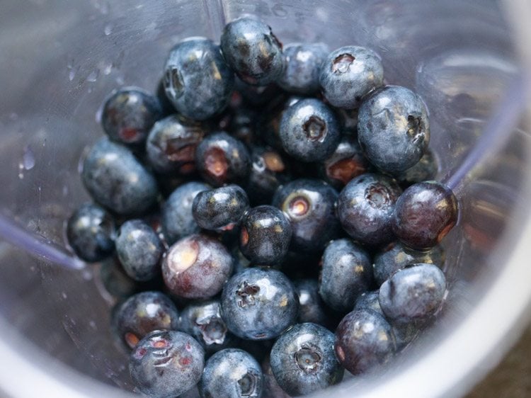 fresh blueberries in the blender jar for making blueberry juice