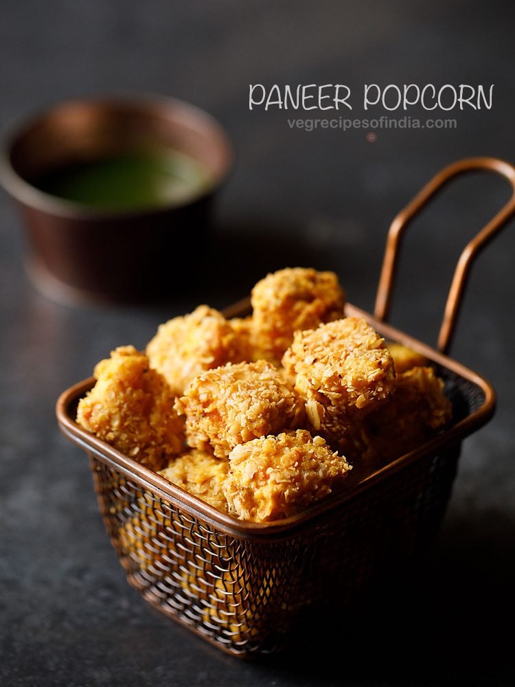 paneer popcorn served in a wired basket with a bowl of green chutney kept on the background and text layovers.