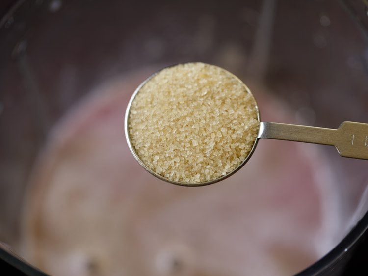 tablespoon of unrefined cane sugar being added to blender.