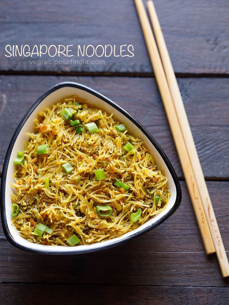 singapore noodles served in a white bowl with chopsticks on the side and text layover.