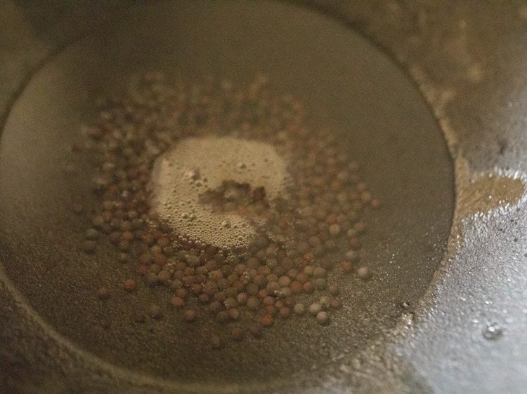 mustard seeds added to hot coconut oil in a pan. 